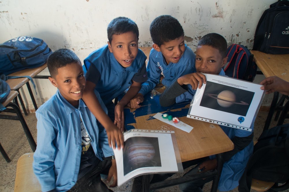 Sahrawi boys showing the scale
models of the Solar System they made
during the Amanar activities at the
Sahrawi refugee camps in 2019.